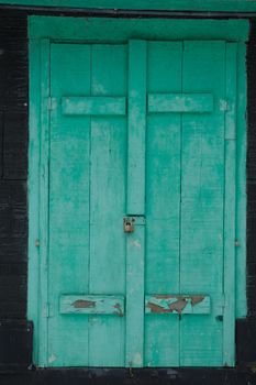 Grungy faded green mildewy shuuters on a waterfront cottage.  Locked on a black cottage in winter