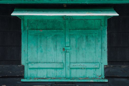 Grungy faded green mildewy shuuters with snow on a waterfront cottage.  Locked on a black cottage in winter