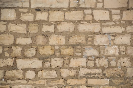 Rugged old limestone wall that is uneven, rustic and filled with cement mortar.