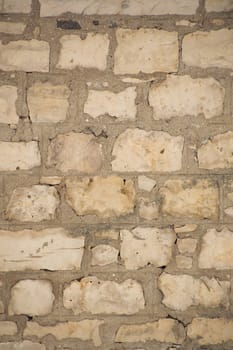 Rugged old limestone wall that is uneven, rustic and filled with cement mortar.