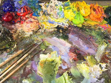 Close up of colorful palette with oil painting and brushes.