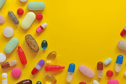 Many colorful pills isolated on yellow background