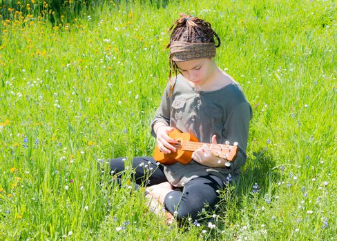 Cute Young Girl With Ukulele in Green Grassy Field