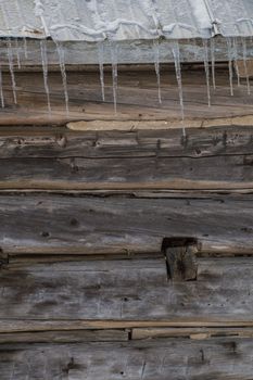 Wintertime snowy old pioneer log cabin barn with icicles. Sunny day.  closeup