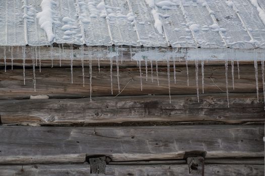 Wintertime snowy old pioneer log cabin barn with icicles. Sunny day.  closeup