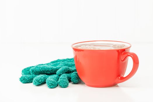Mug of creamy hot chocolate with green winter gloves.