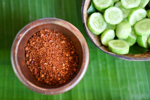 Roasted chili in bowl baked clay with fresh cucumber, Thai food.