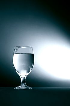 One glass of water on dark background with free space