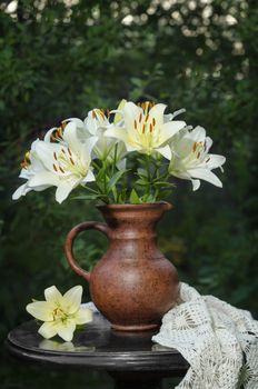 Bouquet of white lilies on the old table in the summer garden. Low key, selective focus, space for text.