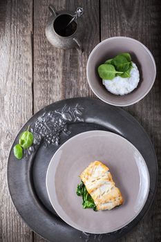 Fried cod fillets and spinach served on a table
