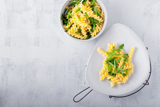 Pasta salad with asparagus and arugula on a white surface