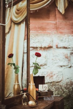 rose in a bottle and perfume, mouthpiece, ashtray on the dressing table