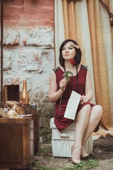 retro girl sitting at a dressing table with a letter and red rose in your hands