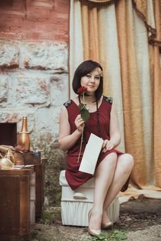 retro girl sitting at a dressing table with a letter and red rose in your hands