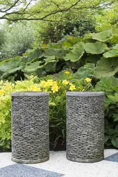 garden with big vases made of gravel with yellow plants as background