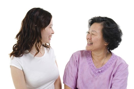 Portrait of Asian senior mother and adult daughter smiling and looking at each other, isolated on white background.