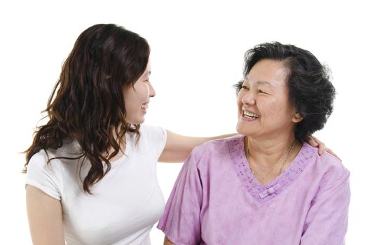 Portrait of Asian senior mother and adult daughter talking and looking at each other, isolated on white background.