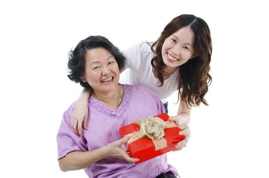 Celebrating mothers day or birthday. Portrait of Asian senior parent getting a gift box from adult daughter, isolated on white background.