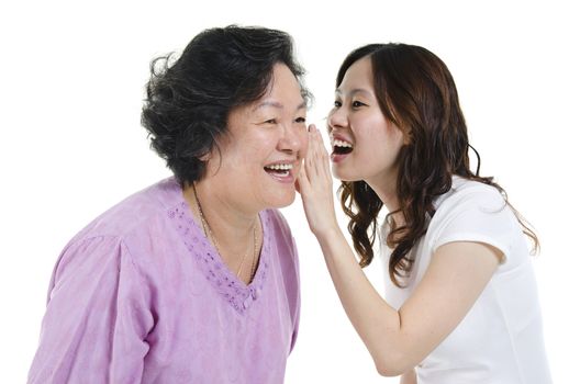 Portrait of Asian adult daughter sharing secrets to her senior mother, isolated on white background.
