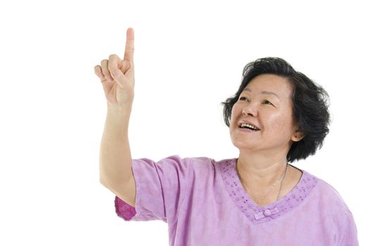 Portrait of Asian senior adult woman smiling and finger pointing at blank copy space, isolated on white background.