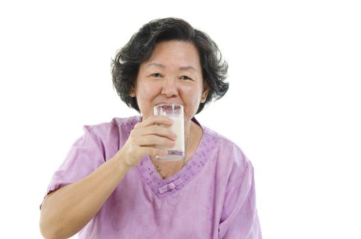 Portrait of Asian senior adult woman drinking a glass soy milk, isolated on white background.