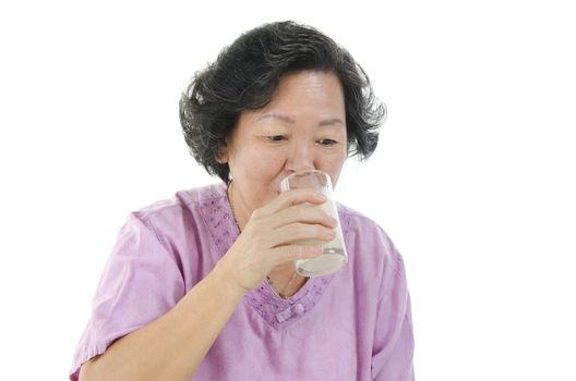 Portrait of healthy 60s Asian senior adult woman drinking a glass soy milk, isolated on white background.