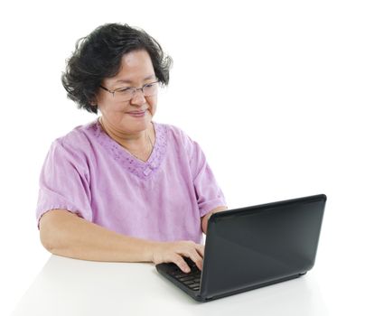 Portrait of modern 60s Asian senior adult woman using laptop computer, isolated on white background.