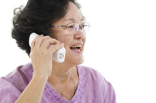 Portrait of 60s Asian senior adult woman calling on telephone, isolated on white background.
