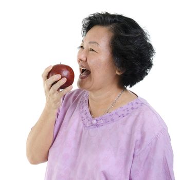Elderly healthy diet. Portrait of happy 60s Asian senior adult woman eating an apple, isolated on white background.