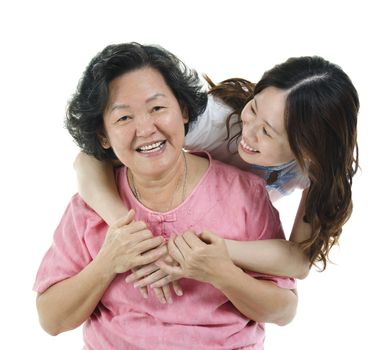 Portrait of Asian adult daughter embracing elderly mother and smiling, isolated on white background.