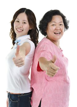 Portrait of Asian senior mother and adult daughter smiling and giving thumbs up hand sign, isolated on white background.
