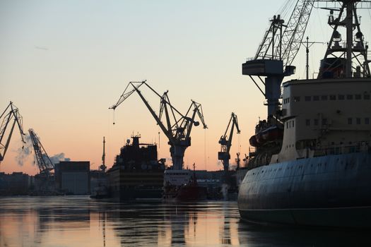 seaport silhouettes of ships and portal cranes in evening sky