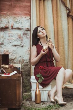 retro girl sitting at a dressing table and holding bottle of perfume in hand