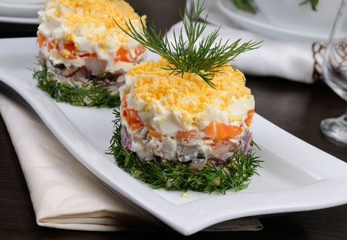 salad stacked chopped herring with potatoes, carrots, onions, egg with mayonnaise strewn with grated egg yolk