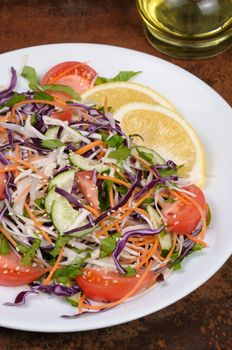 Salad of white and blue chopped cabbage, carrots, cucumber, tomato dressed with oil, lemon, sesame