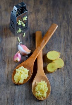 garlic and ginger in wooden spoons on wooden table