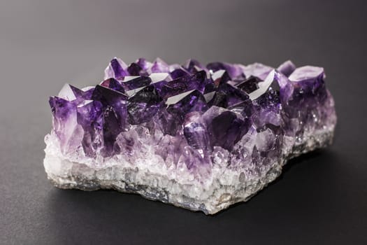 An amethyst stone placed on black background. Horizontal studio shot.