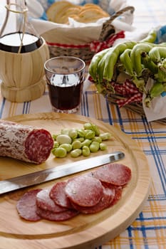 Meat chopping board of traditional Italian salami with broad bean and red wine