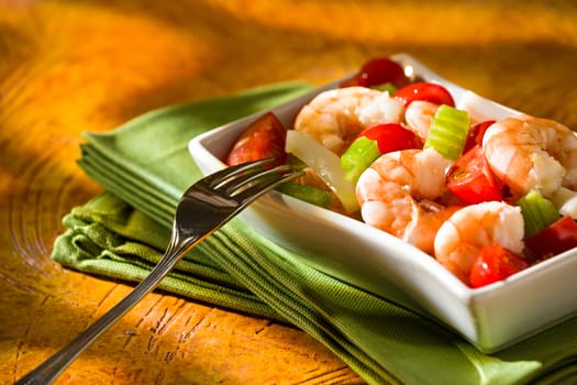 Close up of shrimp salad with squid tomatoes celery inside a white bowl