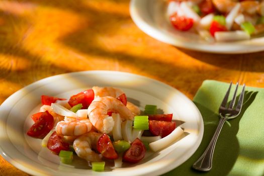 Shrimp salad with squid tomatoes and celery over an orange background