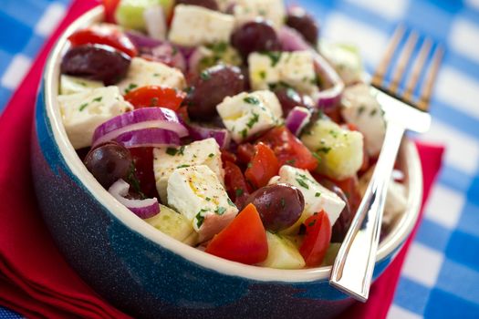 Close up of greek salad with feta cheese tomatoes cucumber olives and onions over a red napkin