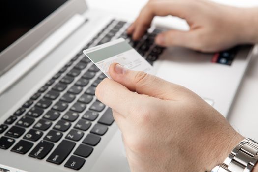 Hands holding a credit card and using laptop computer close up