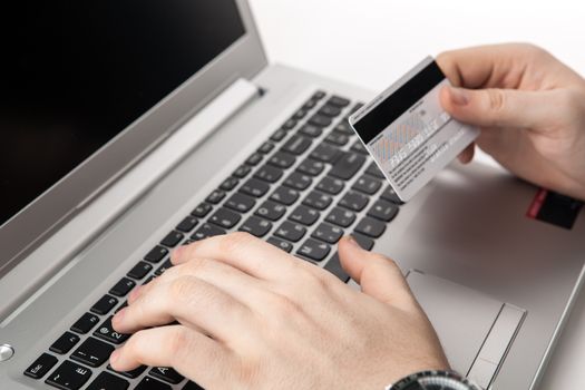 Hands holding a credit card and using laptop computer close up