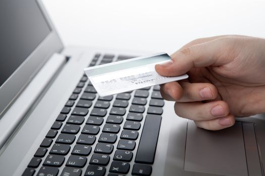 Hands holding a credit card and using laptop computer close up