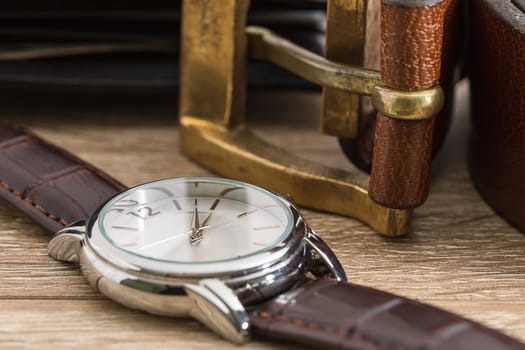Close up wristwatch and brown leather belt on wood table
