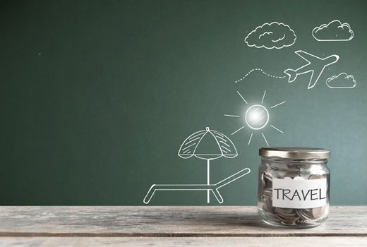 Travel savings jar by a chalkboard with vacation themed sketches 