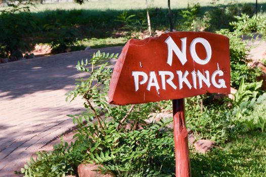 Non-parking sign in white letters on a wooden background at the entrance of a hotel