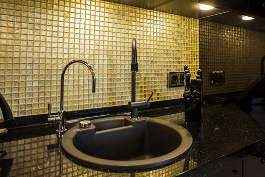 Kitchen desktop with a sink and faucet finishing golden mosaic and black glitter