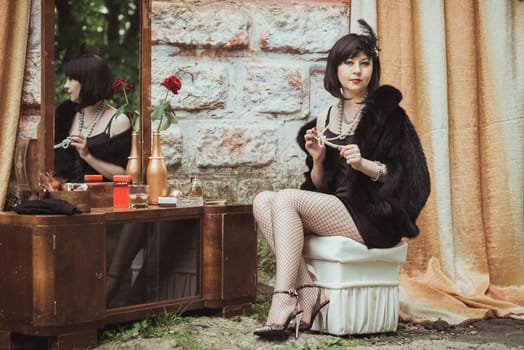 retro girl sitting at a dressing table and holding a necklace in hands