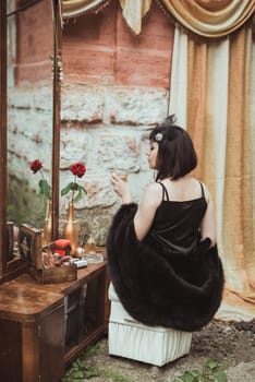 retro girl sitting at a dressing table and holding a glass of alcohol in hand